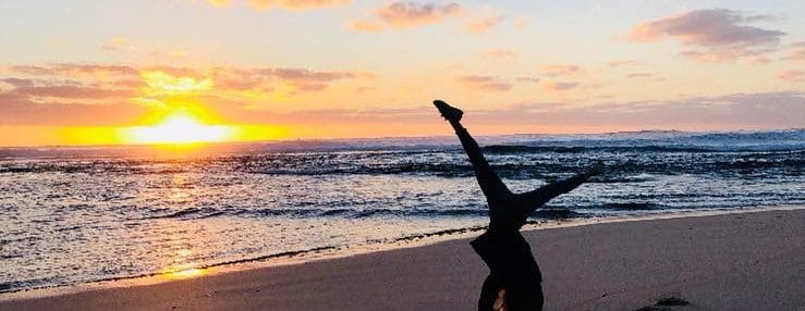 Reasons to Leave Your Hometown. Solo Travel. Girls silhoette doing a cartwheel on a beach during sunset.