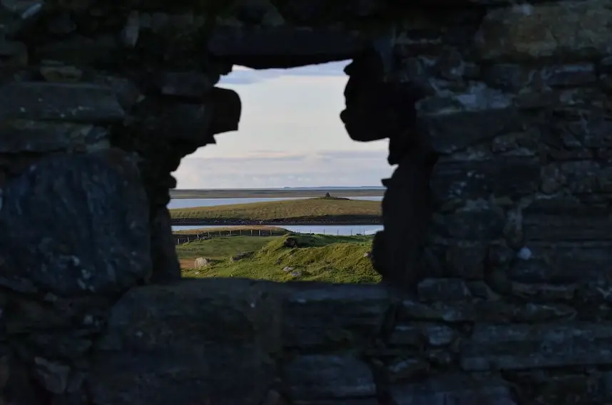 View of country side from a large hole in a stone wall