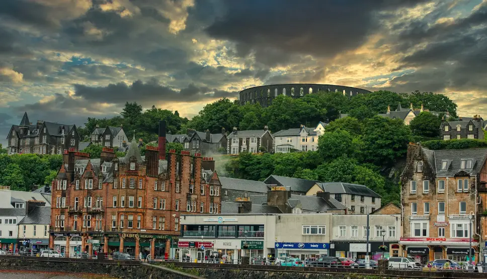 View of Oban from the coast, houses and shops in the foreground and the McCaigs Tower in the background