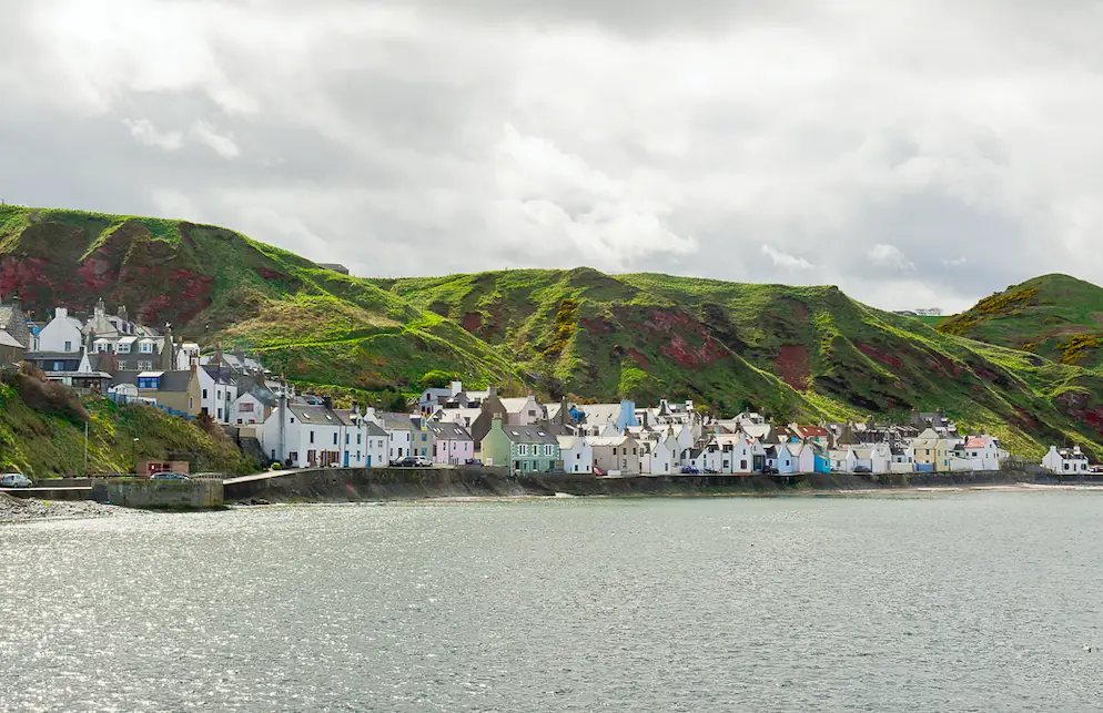 View of Gardenstown. A line of houses along the coast at a bottom of a cliff.