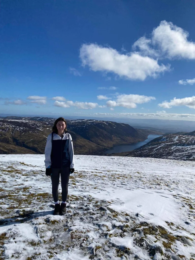 Ben Chonzie Girl at summit of snow covered Ben Chonzie. Loch can be seen in background