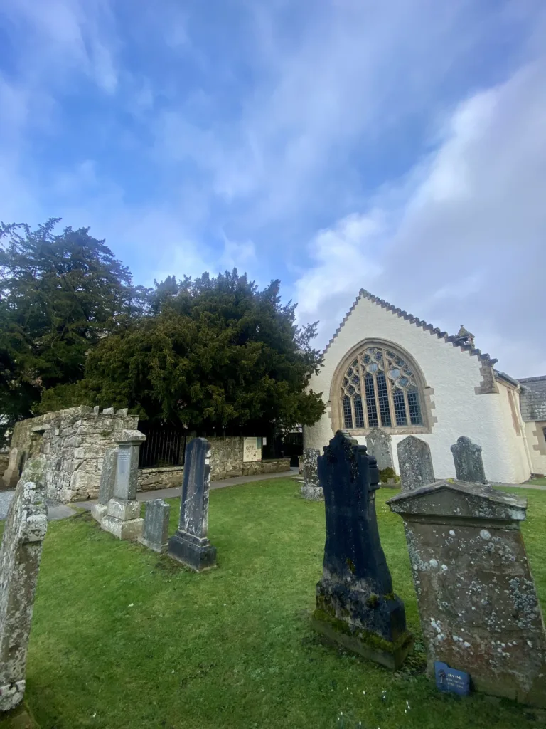 Fortingall Yew Tree Fortingall graves stones and church. The tree is in the background.