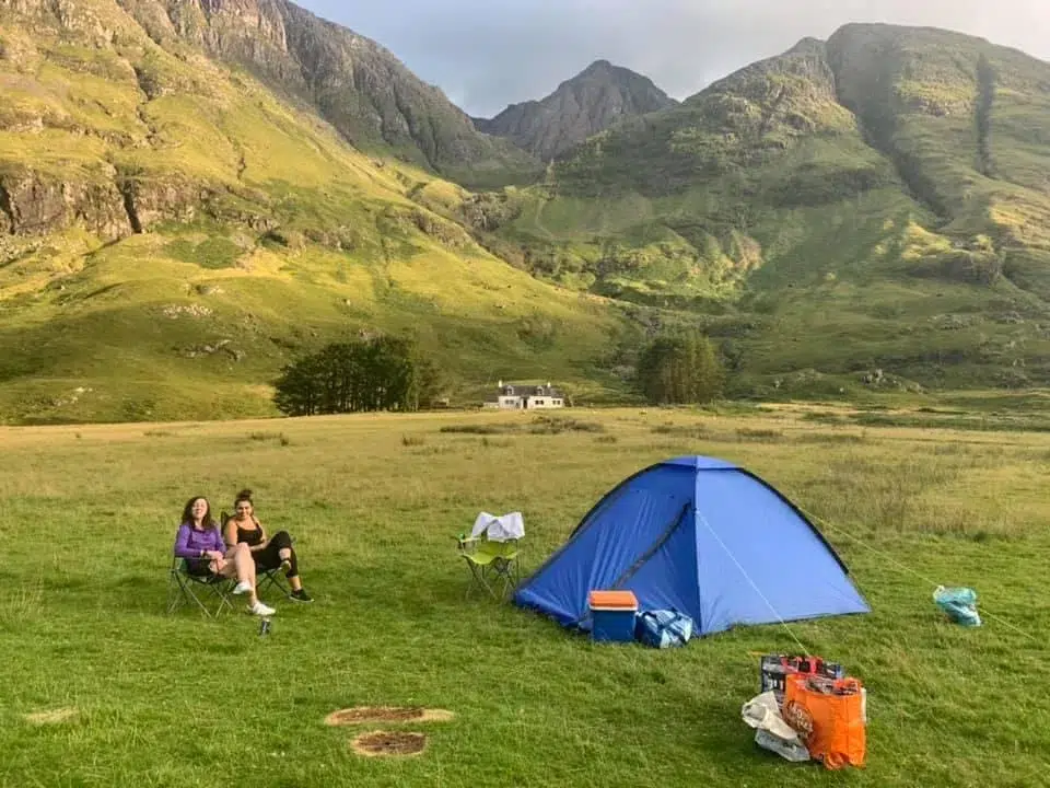 Glencoe Valley. Tent and two girls in the foreground. Mountains in the background.