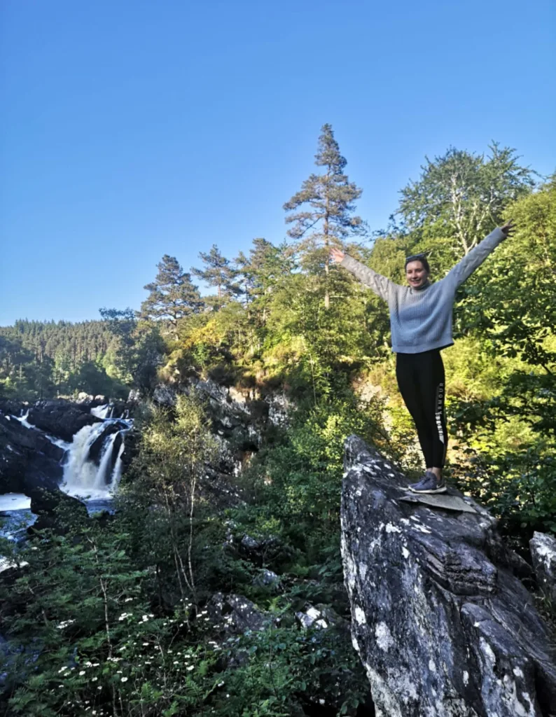 Girl standing on rock in front of Rogie Falls