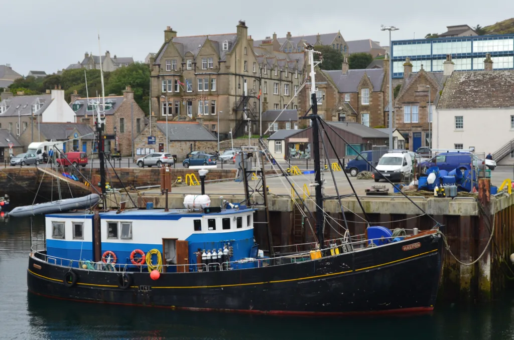 Port photo of boat in foreground in Stromness.